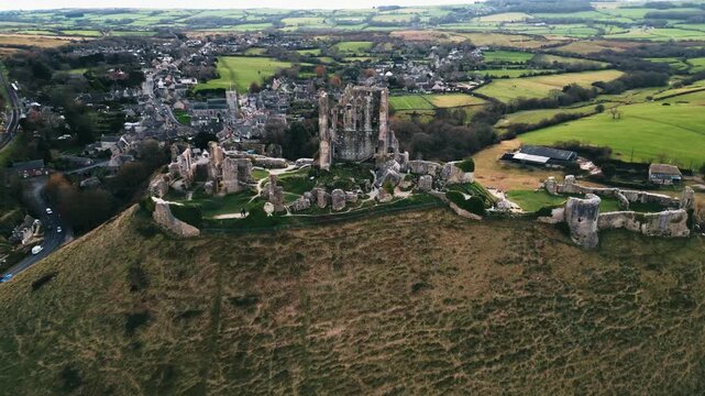 Aerial Drone Footage of Corfe Castle in England &mdash; Historic Medieval Ruins, Scenic Countryside Views, and Dramatic Ancient Landmark Rising Above the Landscape