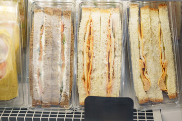 Sandwiches displayed on a shelf in a market with various fillings and bread types