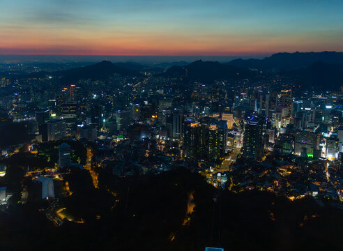 Seoul City Illuminated at Dusk With Mountains in the Background