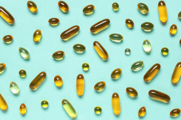 Vitamin E capsules on turquoise background