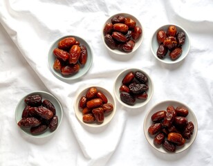 Seven small ceramic bowls, each filled with dates of varying shades and textures, placed on a rumpled white cloth.