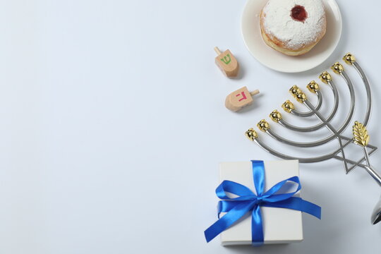 Hanukkah celebration with menorah, dreams, gifts and traditional donuts on a white background.