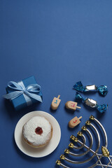 Hanukkah celebration with menorah, dreams, gifts and traditional donuts on blue background.
