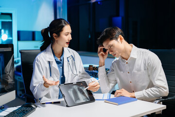 Obraz premium Asian doctor comforting stressed patient in hospital office, showing compassion, empathy, and emotional support during mental health consultation.