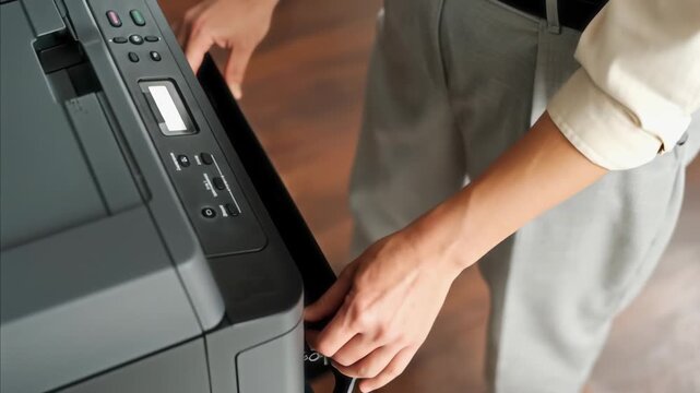 AI animated top view of hands and midsection of unrecognizable female employee loading stack of blank paper sheets into photocopier tray and closing it to make scan copies of documents in office
