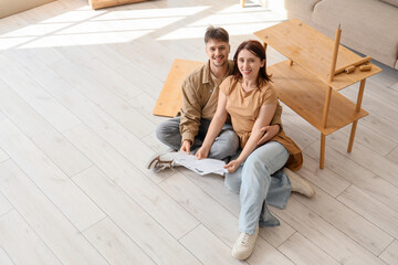 Young couple with instructions assembling shelf unit at home