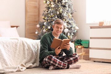 Young man reading book in bedroom on Christmas eve
