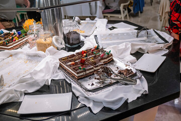 Chocolate cake on buffet table with jars and tongs.
