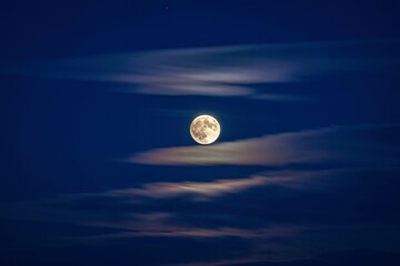 Full moon shines through wispy clouds on a clear night