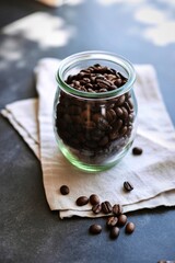Glass jar filled with roasted coffee beans on a napkin