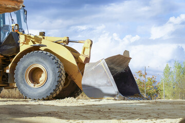 Fototapeta premium ronda,malaga,spain Yellow wheel loader standing on a dusty construction site with a large bucket and heavy tires under a blue sky