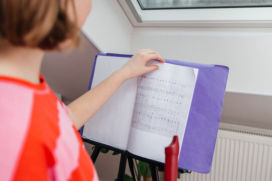 A girl turns over notes while playing the flute. A teenage girl learns to play the flute