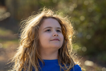 Fototapeta premium Carefree kid in a meadow. Child imagining. Outdoor portrait of a dreamer kid. Freedom and innocence in childhood. Cute kid outdoor portrait. Dreamy kids face. Carefree childhood. Dreamy child.