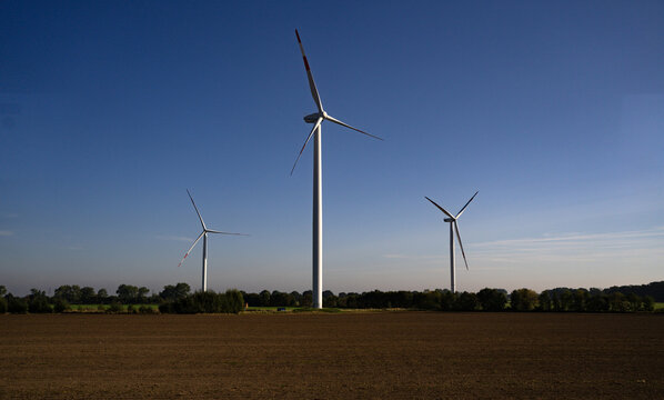 Wind energy powers the countryside. Renewable turbines rotate all day. The blue sky covers the windfarm. Modern blades generate electricity. The landscape supports green power. - Powered by Adobe