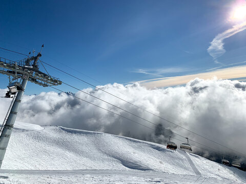 Ski lift moving above snowy slopes and clouds