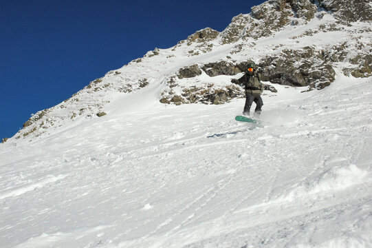 Snowboarder riding freeride down rocky slope