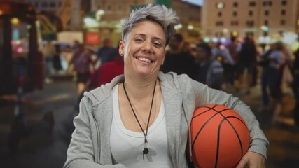 Woman coach with short hair holding orange basketball on bustling city street; confidence determination empowerment. - Powered by Adobe