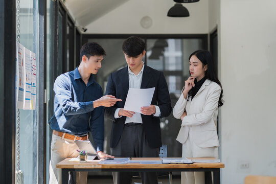 Young business team discussing project documents during meeting - Powered by Adobe