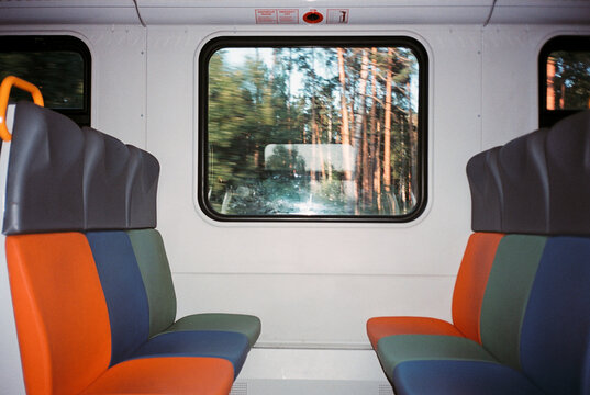 Fototapeta Colorful train seats with forest view through window