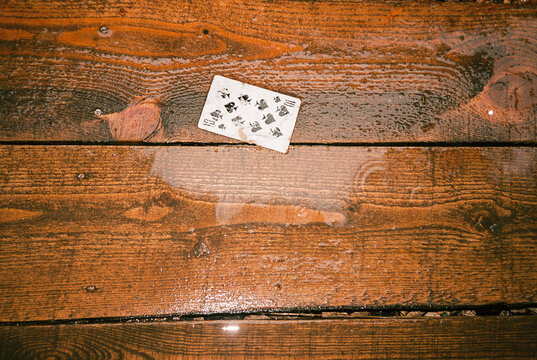 Playing card lying on wet wooden deck after rain