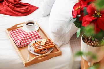 Christmas plant poinsettia and tasty breakfast on bed in room