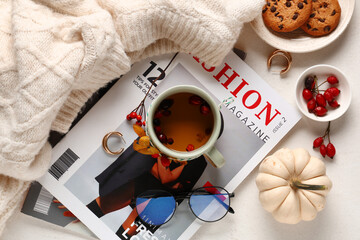Composition with mug of rose hip tea, cookies, sweater and magazines on white background, closeup