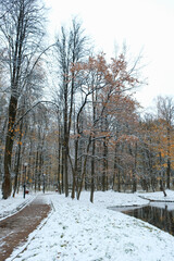 Beautiful landscape with road, pond and trees covered first snow in autumnal park. Fall season nature image. snowy cold weather. late autumn or early winter season. october, november months calendar