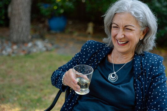 Smiling senior woman outdoors with a glass of wine