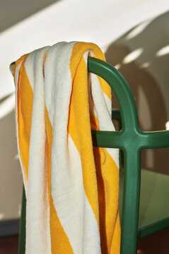 Bright yellow and white striped towel draped over a green chair