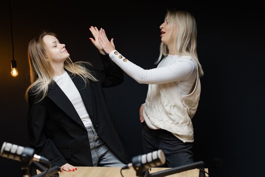 Two podcasters pointing and laughing during a recording session