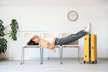 Sleeping Asian woman waiting for her flight on chairs in airport lounge