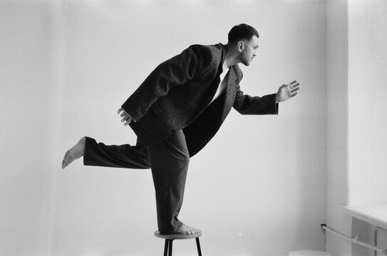 Man balancing on a stool in a minimal room