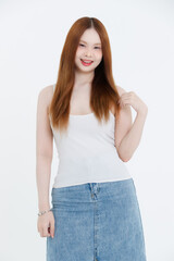 Obraz premium Studio portrait of asian attractive beautiful young woman in white tank top, denim skirt, posing smile on white background, minimal fashion style casual outfit lifestyle clothing advertising concept.