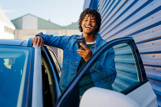 Man using smartphone laughing by car