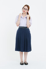 Studio portrait of asian cheerful young teenage woman wearing black framed eyeglasses white blouse navy pleated skirt posing on white background student high school uniform education lifestyle concept