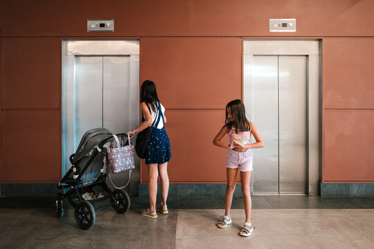 Mother and daughter waiting for the lift with a pram.