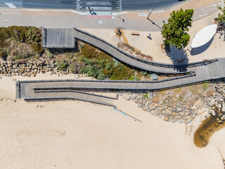 Wooden boardwalk ramp from a roadside down to a sandy beach