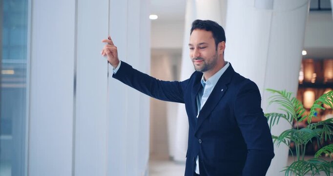 Pensive European professional man in a navy suit checking his time and contemplating while waiting in a bright modern corporate office hallway