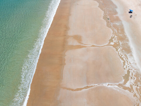 Wave and sand patterns along a wide sandy beach