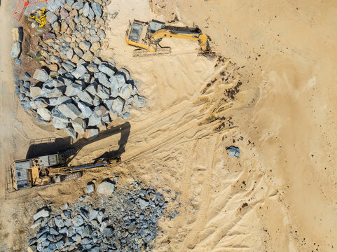 Excavators building a rock wall on a beach