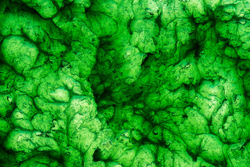 Abstract texture of green bearing grease illuminated from below, forming organic shapes,...