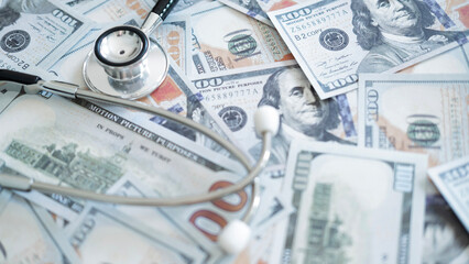 Close up stethoscope on hundred dollar bills symbolizing rising medical fees, expensive treatment payments and healthcare financial pressure.