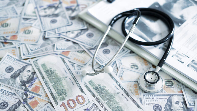 Stethoscope and medical documents with money expressing health insurance paperwork, billing issues and financial risk of treatment plans. - Powered by Adobe
