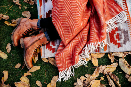 Fall mood. Woman lying in the grass covered by with a wool blanket.