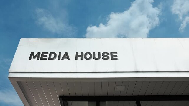 A media house word sign prominently displayed on a modern corporate building under a clear blue sky, symbolizing news, publishing, content creation, and broadcasting
