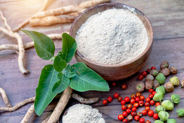Fototapeta premium Ashwagandha Roots and powder known as Withania somnifera in white bowl on wooden background. Indian ginseng, poison gooseberry, or winter cherry. Herbal adaptogen ayurvedic medicine.