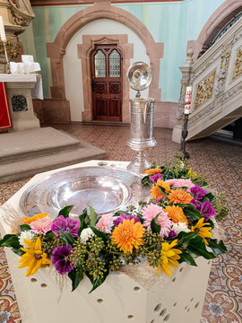 Taufschale und Taufkanne mit Blumen geschm&uuml;ckt in einer Kirche