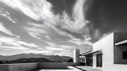 Obraz premium Modern minimalist residence features stark white walls contrasted against a dramatic sky over distant hills