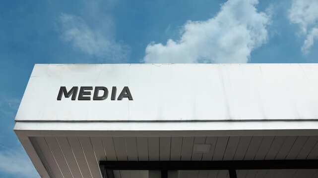 A media word sign prominently displayed on a sleek building under a clear blue sky, symbolizing communication, information, broadcasting, and content industries