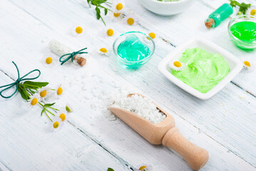 beauty product samples with chamomile flowers on white wooden table